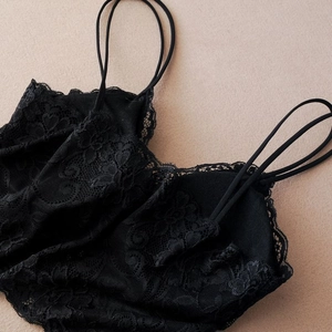 Detail of black lace camisole with floral embroidery and thin double shoulder straps