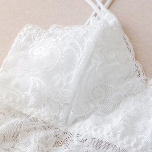Macro detail of intricate white floral lace texture on a camisole with thin straps