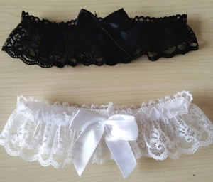 Vue détaillée de jarretières en dentelle noire et blanche avec nœuds en satin soyeux