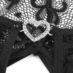 Macro shot of heart-shaped metal buckle with sparkling rhinestones on black lace lingerie