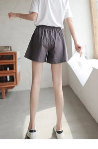 Rear view of women's dark gray loose cotton shorts with elastic waist in a cozy home setting