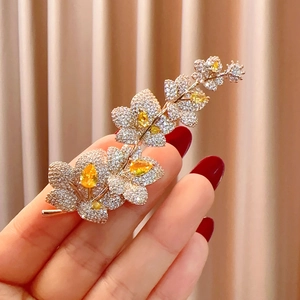 Dettaglio spilla a fiore dorata di lusso con zirconi bianchi e pietra preziosa gialla