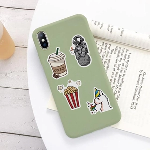 Detail of light green silicone phone case with cute cartoon stickers on a wooden table