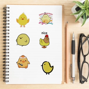 Detalle de lindas pegatinas de pollitos amarillos en un cuaderno con papelería decorativa