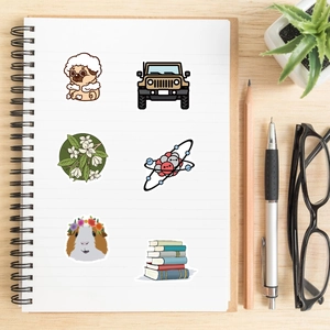 Various cute cartoon stickers organized on a spiral notebook with lifestyle accessories