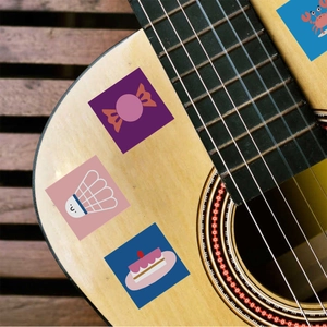 Close-up of waterproof cartoon stickers showing candy and crab designs on a guitar