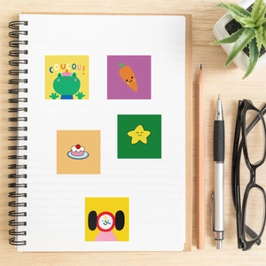 Close-up of colorful cartoon stickers like frogs and carrots on a spiral notebook