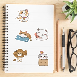 Close-up of cute Japanese cartoon cat stickers on a notebook with desk accessories