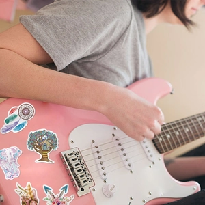 Colorful Bohemian stickers on a pink electric guitar featuring dreamcatcher and elephant