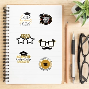 Close-up of gold and black graduation stickers on a notebook with premium glitter details