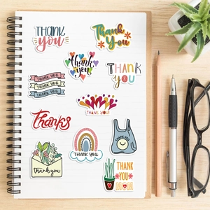 Flat lay of colorful inspirational thank you stickers on a white notebook page
