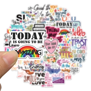 Close-up of hand holding a rainbow motivational sticker with colorful sticker set background