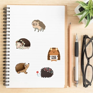 Detailed view of waterproof cartoon hedgehog stickers on a notebook in a workspace