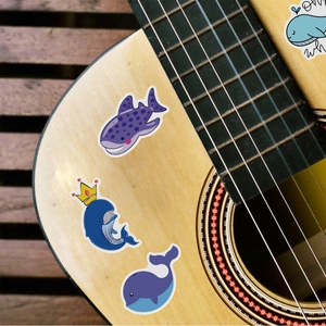 Detailed shot of cute waterproof whale stickers on a wooden guitar for decoration