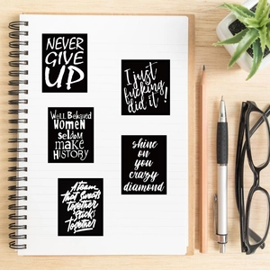 Waterproof black and white inspirational quote stickers on a white notebook with accessories