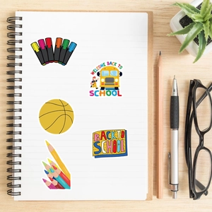 Detail of waterproof school stickers with bus and pencil motifs on a notebook
