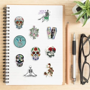 Nahaufnahme bunter wasserfester Totenkopf-Sticker und Blumen-Skelett-Dekore auf Notizbuch