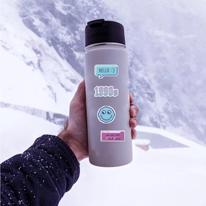 Detailed view of purple pixel art stickers on a grey water bottle with mountain backdrop