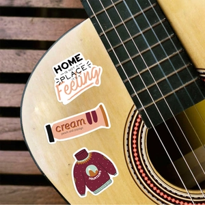 Close-up of waterproof cartoon stickers with creative illustrations applied on a guitar