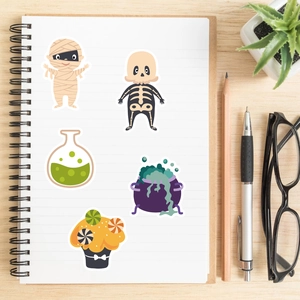 Detailed view of Halloween cartoon stickers on a white notebook with stationery accessories