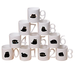 Detail of white ceramic mugs featuring unique 0-9 number handles and cartoon cat graphics