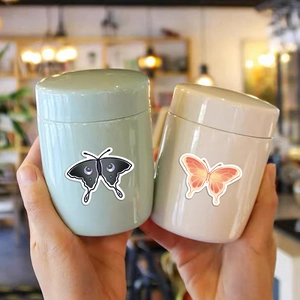 Detail view of colorful butterfly stickers on mini mint green and cream white storage jars