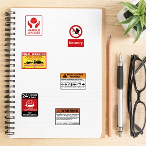 Detailed view of warning and caution graffiti stickers displayed on a white notebook