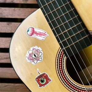 Detailed view of surreal eyeball graffiti stickers applied to a wooden guitar surface