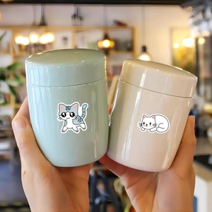 Detail view of mini ceramic storage canisters featuring cute cartoon cat stickers