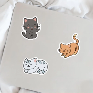 Three cute cartoon cat stickers on a laptop surface for DIY decoration