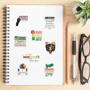 50pcs Juneteenth stickers with Pan-African colors and fists on a minimalist wooden desk