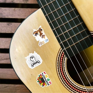 Detail shot of Juneteenth Freedom stickers applied to a light wood guitar surface