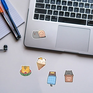 Detail showing cartoon cat stickers on a silver laptop and white desk surface