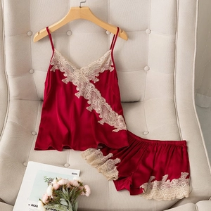 Detail of red silk pajama set with delicate lace trim on V-neck top and matching shorts
