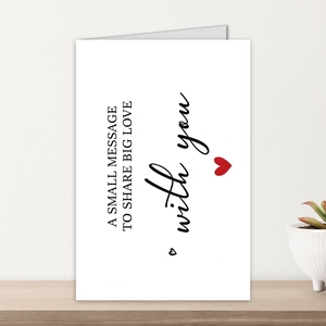 Minimalist white greeting card with red heart and envelope on a wooden table