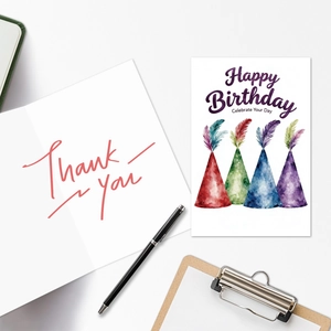 Close-up of watercolor birthday cards and thank you notes on a desk with a pen