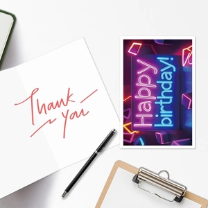 Flat lay of Happy Birthday neon card and red Thank You card set on white desktop