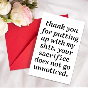 Detail of minimalist white card with red envelope and white rose on silk fabric