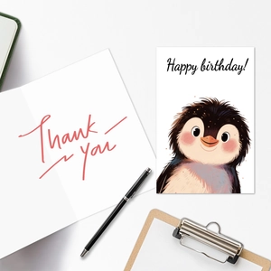 Close-up of cute cartoon penguin happy birthday card and thank you note on desk