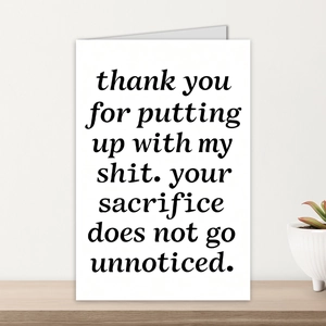 Detail of minimalist white card with humorous text on a wooden desk with a succulent