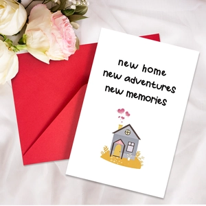 Close-up of new home greeting card with red envelope on elegant white silk and roses