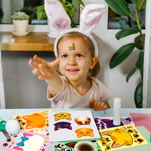 Close-up of a child doing DIY cat face sticker puzzles with creative craft tools