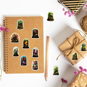 Close-up of vintage floral and butterfly stickers in glass bell jars on a notebook