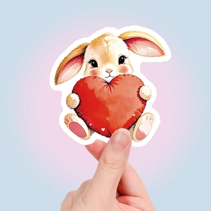 Hand holding a cute watercolor bunny sticker with a red heart for gift decoration