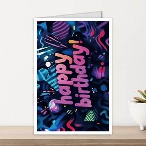 Detail of neon Happy Birthday card with abstract art on a wood table with a plant