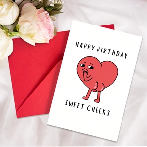 Detail shot of a funny cartoon heart birthday card with a red envelope on white silk