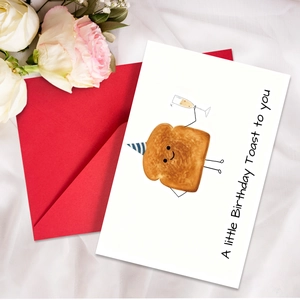 Close-up of birthday toast card with a red envelope on a soft white cloth background