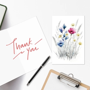 Detailed view of watercolor floral thank you card with artistic stationery on white desk