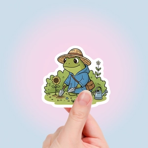 Close-up showing a cute cartoon frog sticker with a gardening theme and white border