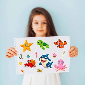 Detail showing a girl holding cartoon sea animal face swap puzzle stickers for DIY kids craft